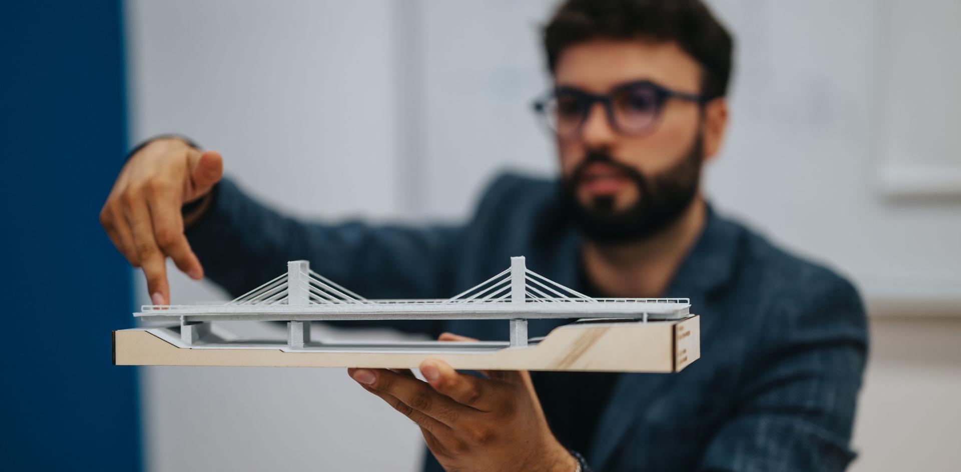 Ein Bauingenieur begutachtet das Modell einer Brücke.