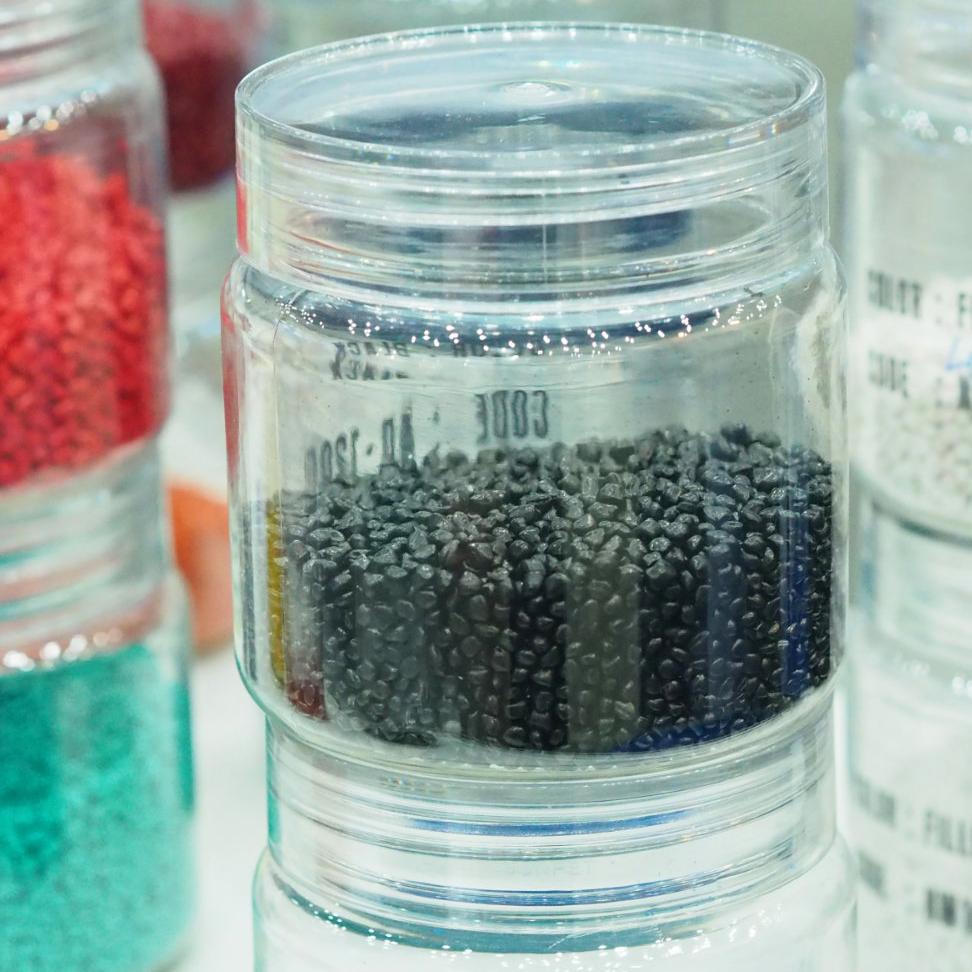 Mehrere aufeinandergestapelte Gläser mit Kunststoff in verschiedensten Farben stehen auf einem Tisch.