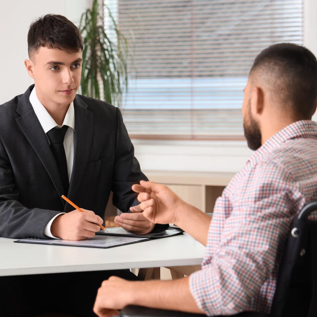 Beratungsgespräch in einer Kanzlei, ein Rechtsanwaltsmitarbeiter im Anzug bespricht Unterlagen mit einem Mandanten.