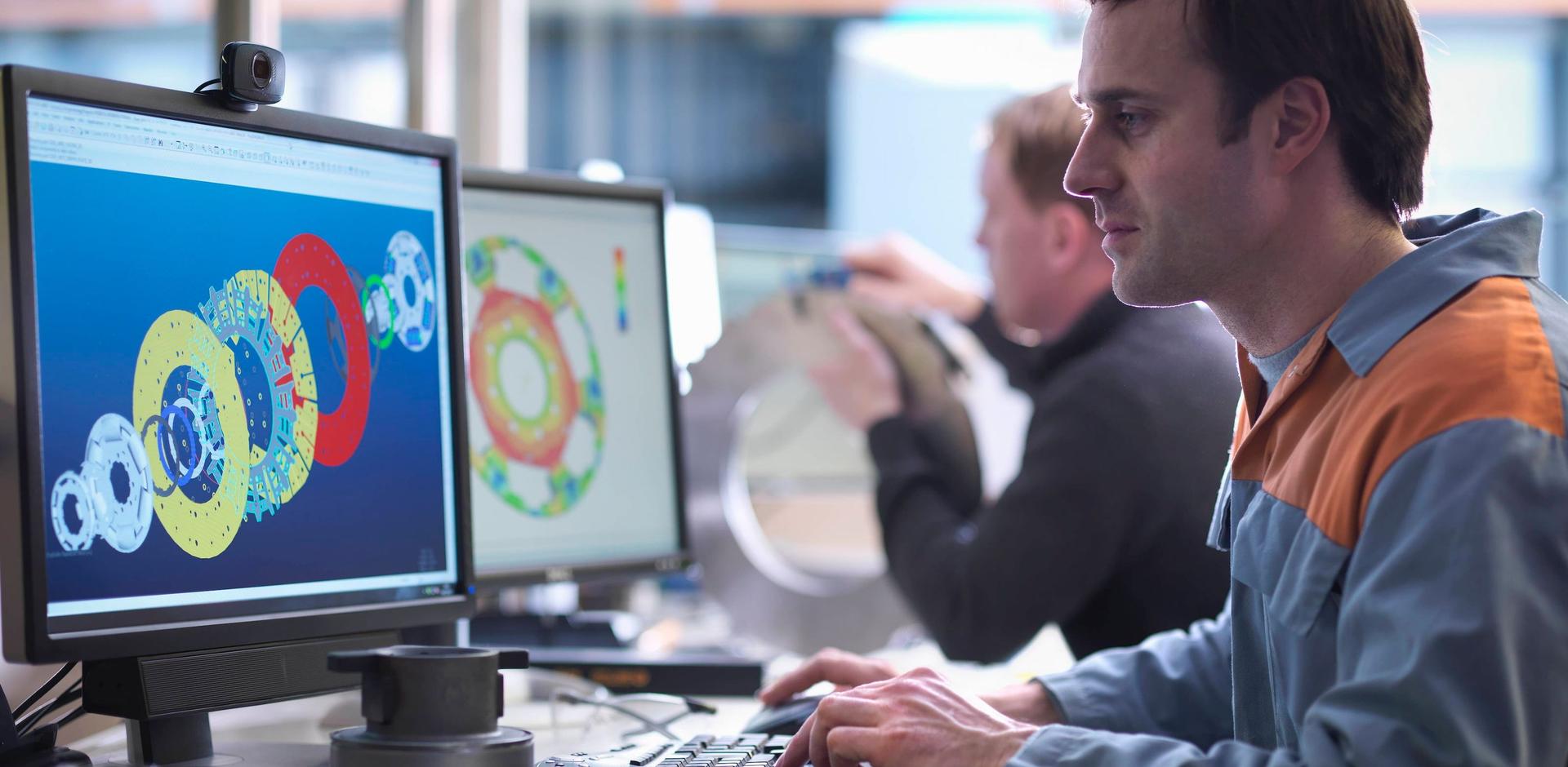 Ein junger Mann, vermutlich ein Technischer Produktdesigner, arbeitet am Computer und erstellt ein digitales Modell mit einem CAD-System.
