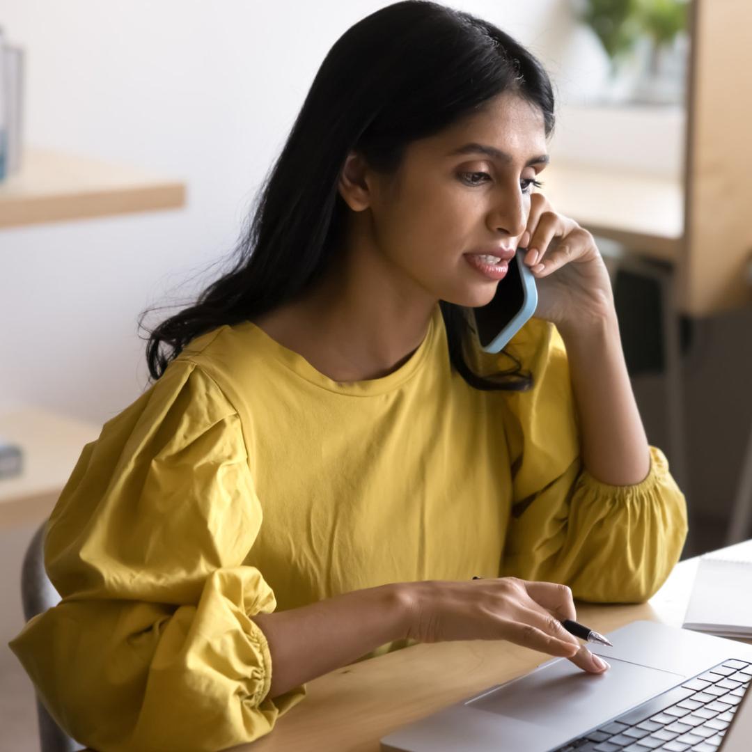 Eine Frau telefoniert und ist am Laptop.