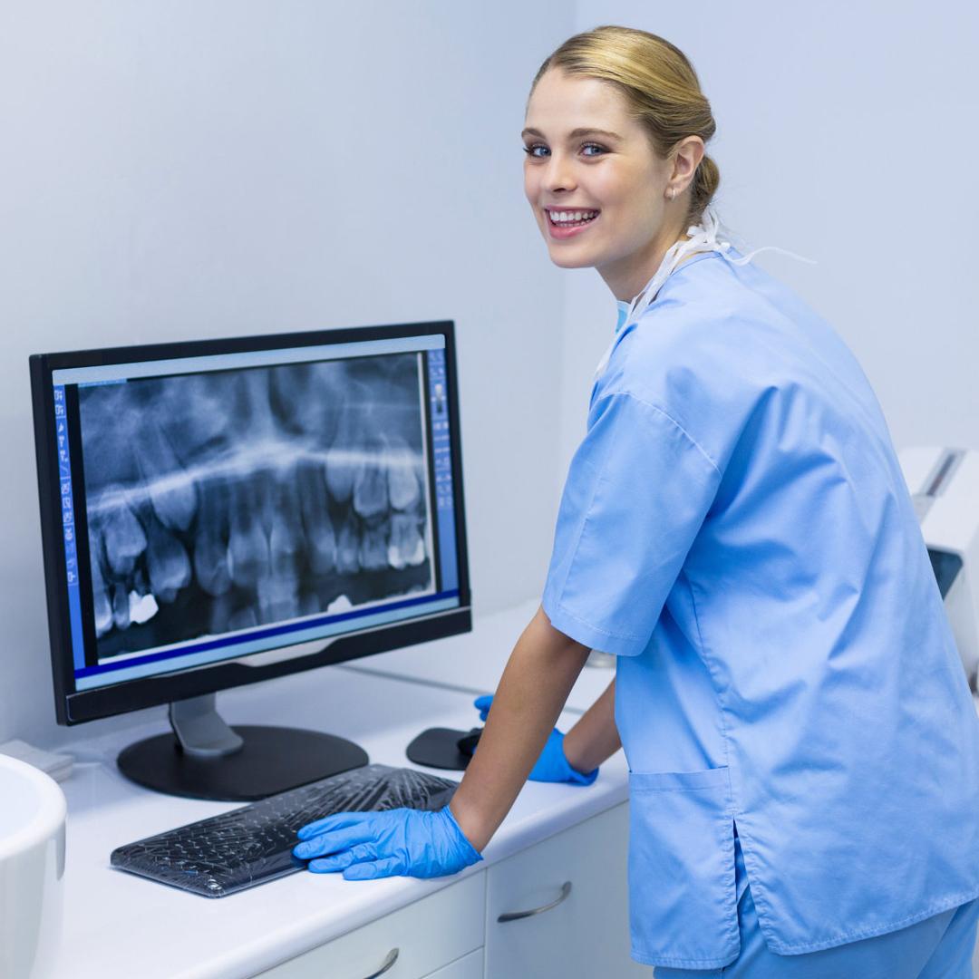 Eine Frau trägt Arbeitskleidung und Handschuhe. Sie schaut sich eine Röntgenaufnahme an.n